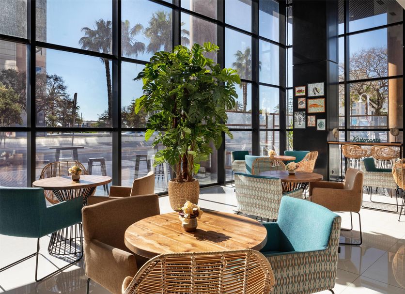 Catalonia Málaga lobby lounge with floor-to-ceiling windows and palm trees outside
