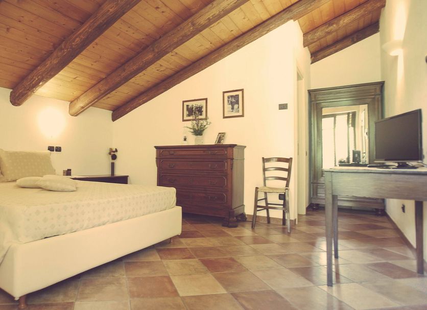 Casa Ressia in Alba guest room with wood-beamed ceiling, bed, dresser and TV