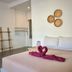 Phangan Great Bay Resort in Ko Pha Ngan bedroom with bed, towel swans, and woven wall decor