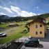 Hotel Valtellina in Livigno, mountain-view hotel with parked cars and grassy alpine slopes