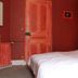 Hôtel De Normandie in Amiens, red-toned guest room with canopy bed and sheer drapes