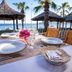 Latanya Park Resort in Bodrum: seaside dining table with ocean view, palm trees, and thatched cabanas