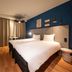 ibis Nogent-sur-Marne room with twin beds, blue accent wall, TV, and small table by curtains