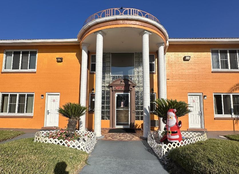 Super Inn By OYO Daytona Beach Near Airport exterior with orange facade, arched entryway and walkway