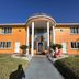 Super Inn By OYO Daytona Beach Near Airport exterior with orange facade, arched entryway and walkway