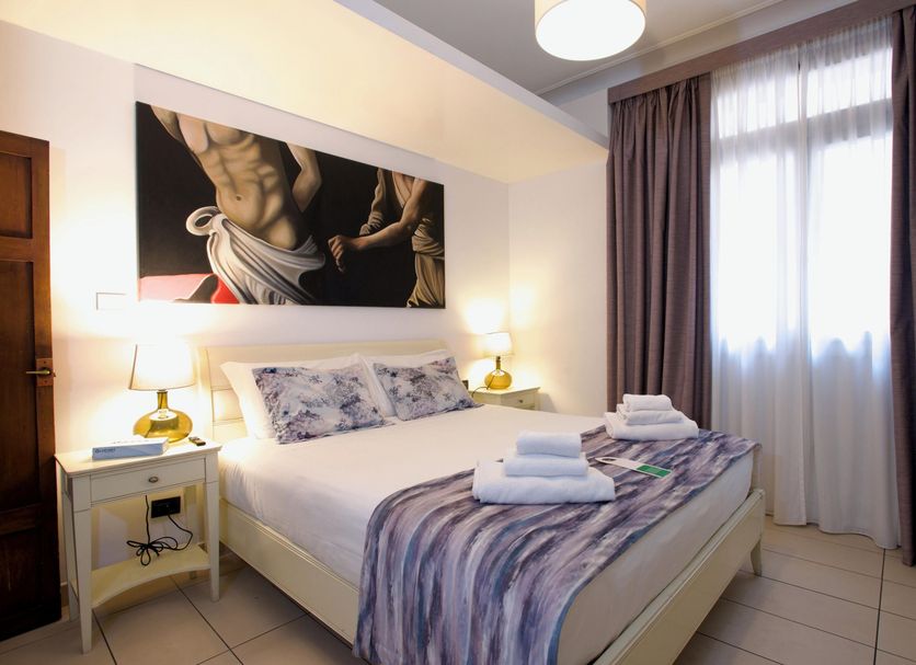 St. Peter' Six Rooms & Suites in Rome, bedroom with king bed, bedside lamps and sheer curtains