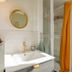 Les Suites de Bellac bathroom with gold round mirror, sink, and glass shower in Bellac