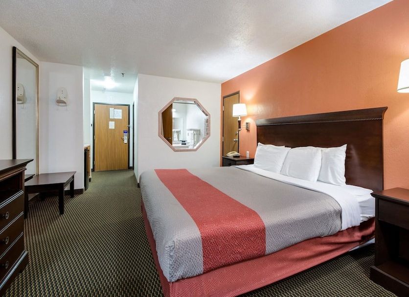 Motel 6 Marion, IL guest room with king bed, desk, wall mirror and orange accent wall