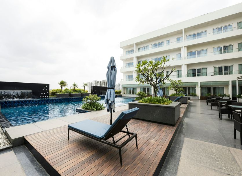 Oakwood Residence Whitefield Bangalore in Bengaluru: outdoor pool with lounge chair and modern hotel facade