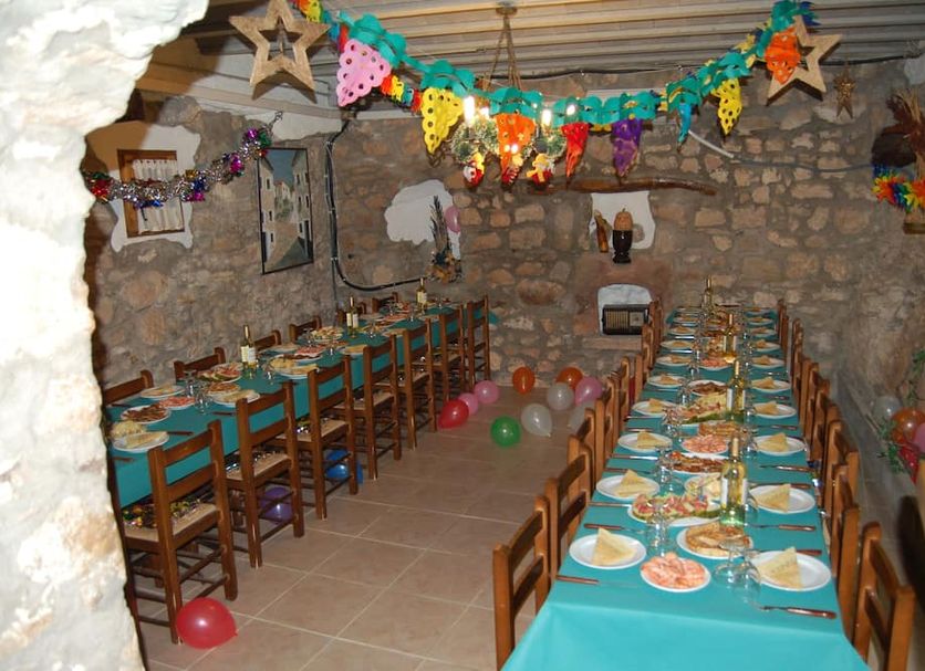 Albergue Rural Cal Picarol dining room in Àger with long set tables, chairs, and festive bunting