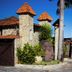 Pousada Villa Das Pedras in Pirenópolis, stone entrance with red-tile roofs and palm trees