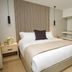 Rio Suites in Tijuana hotel room with a king bed, wood slat accent wall, bedside tables, and wall mirror