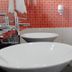 Hotel Dorado Ferial Bogotá bathroom with double white vessel sinks and orange tiled wall