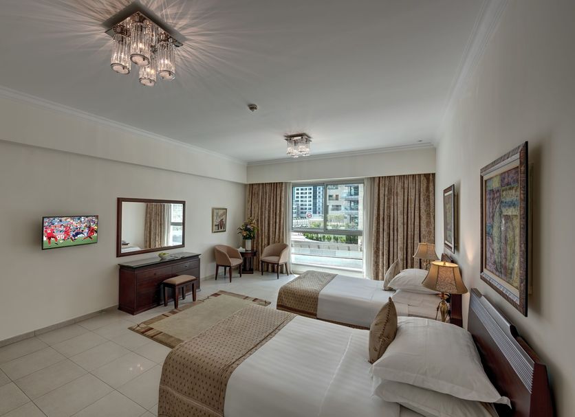 Marina Hotel Apartments in Dubai bedroom with two beds, balcony view, seating area and TV