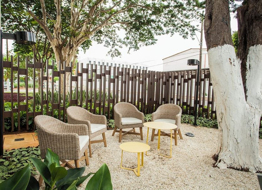 Transamerica Wise Indaiatuba outdoor seating area with wicker chairs, small tables, and trees