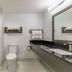 Studio 6 Suites Perris bathroom with tub shower, toilet, vanity and mirror