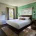 The Stavrand Russian River Valley guest room in Guerneville with king bed, green leaf wallpaper, and patio doors.