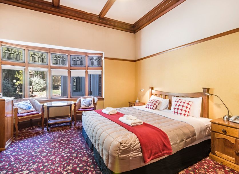 Halswell Lodge Wellington guest room with king bed, bay window seating, and patterned carpet