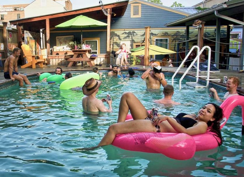 India House Hostel in New Orleans pool scene with guests lounging on floaties and a ladder