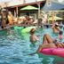 India House Hostel in New Orleans pool scene with guests lounging on floaties and a ladder