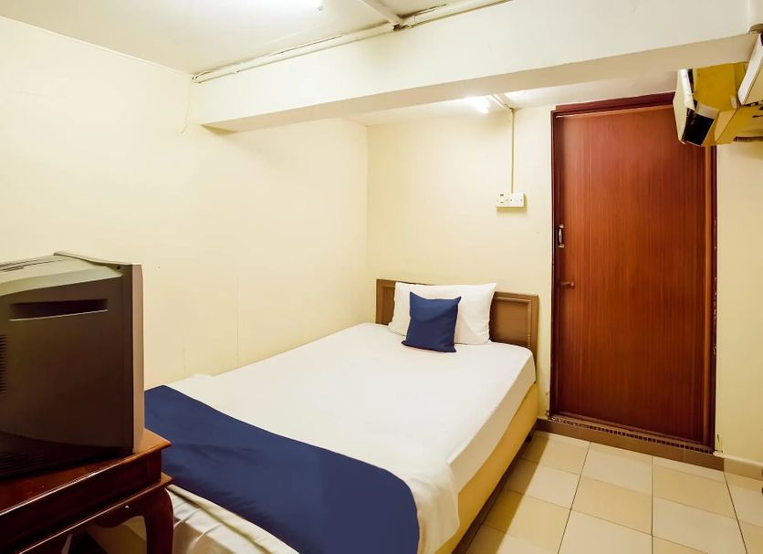 Casavilla Travellers Lodge Pudu in Kuala Lumpur: compact single room with bed, TV, and wooden door