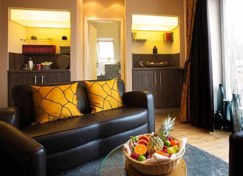 Regiohotel Berghotel Ilsenburg lounge with black sofa, fruit basket, and balcony door