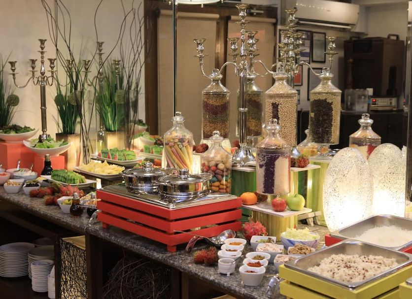 Buffet spread at Malayan Plaza Hotel in Manila with dishes, desserts, glass dispensers, and floral decor