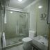 Onyx Hotel Bishkek bathroom with glass shower enclosure, toilet, and wall-mounted sink in Bishkek