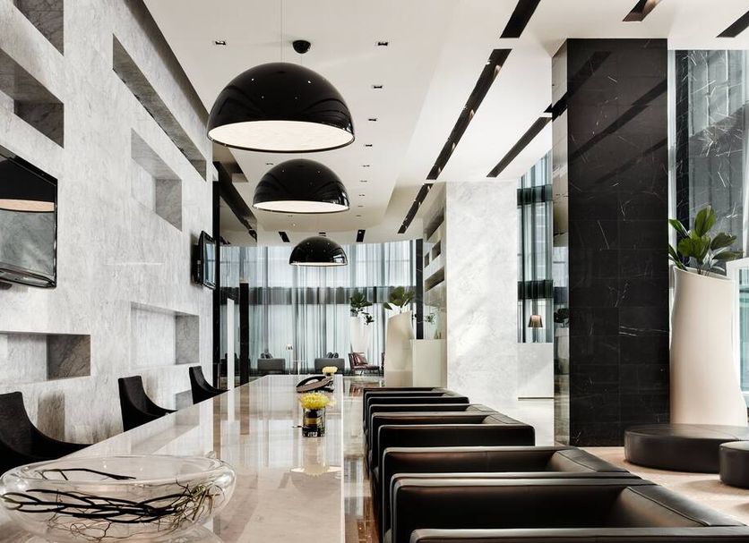 S31 Sukhumvit Hotel in Bangkok lobby with long marble table, black chairs, and pendant lights