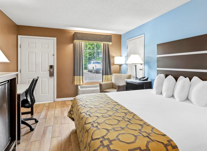 Baymont by Wyndham Forest City guest room with king bed, desk, chair, and window view