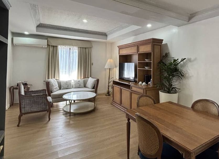 Queen Margarette Hotel Lucena living area with sofa, armchairs, TV cabinet, and dining table
