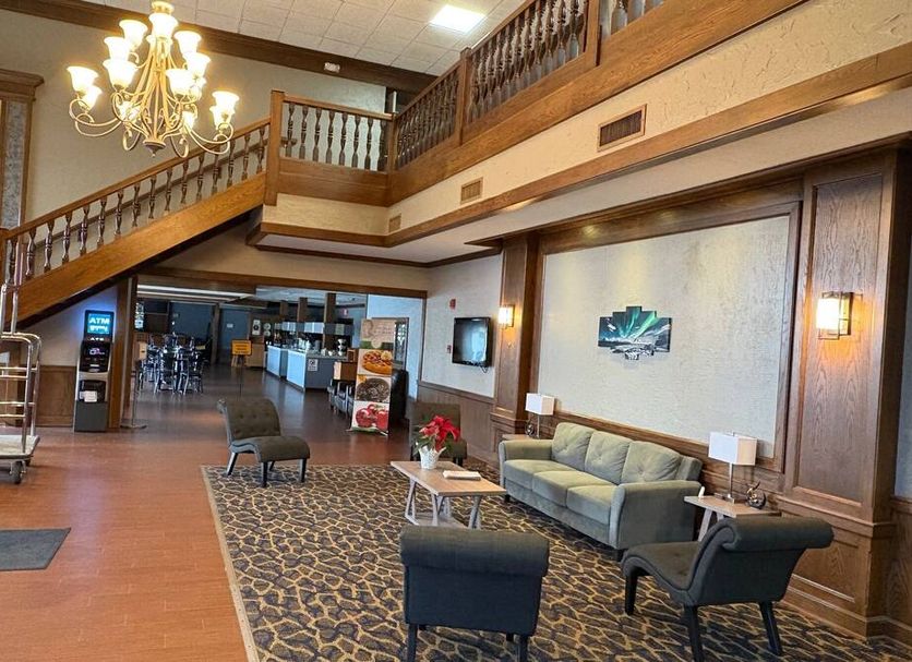 Quality Inn Perrysburg lobby with chandelier, staircase, seating area and wood-paneled walls