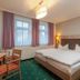 Stolberger Hof in Südharz guest room with double bed, desk, chairs, and large windows with purple curtains