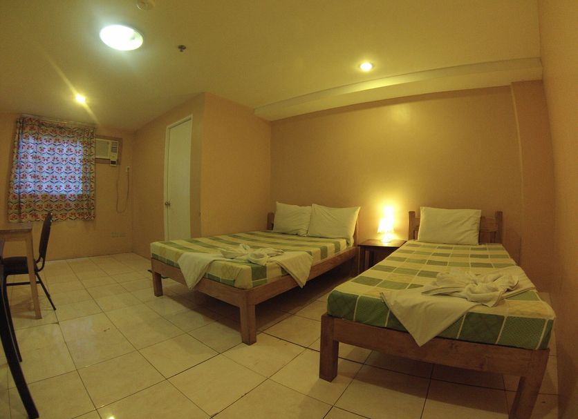 Lylie Hotel Mandaue City room with two single beds, tiled floor, desk, window, and warm lighting