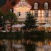 Landhaus Zu den Rothen Forellen in Ilsenburg, lakeside hotel terrace glowing at dusk with reflections