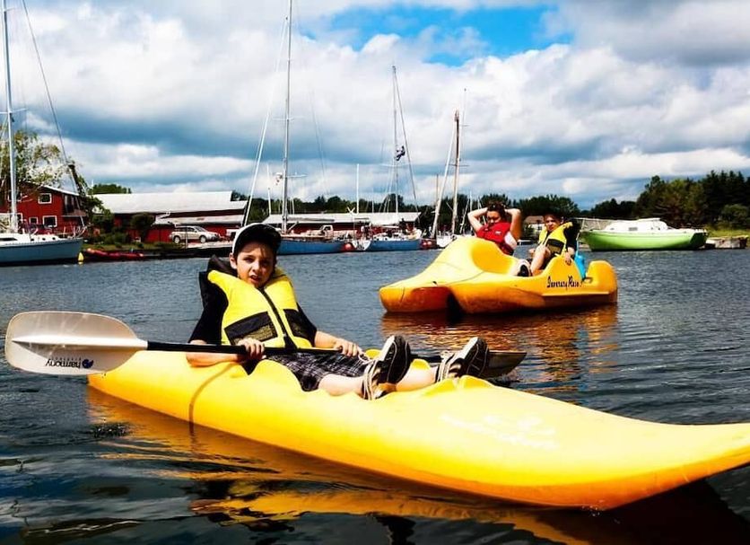Inverary Resort in Baddeck: yellow kayaks on the water with sailboats and cloudy sky