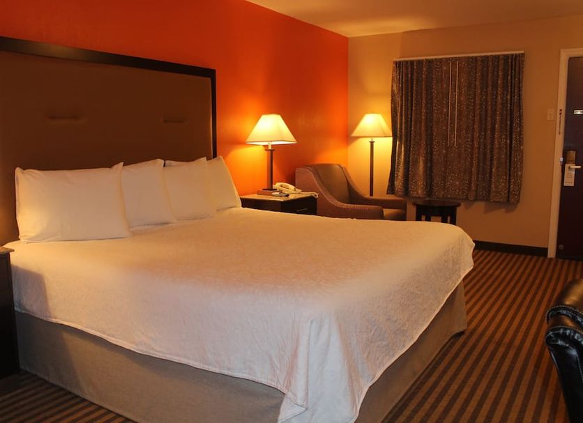 Travelodge by Wyndham Bellmawr room with king bed, two lamps, chair and window drapes in Bellmawr