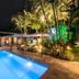 Casa Nostra Boutique Hotel in Paraty with a lit outdoor pool, palm trees, and patio seating at night