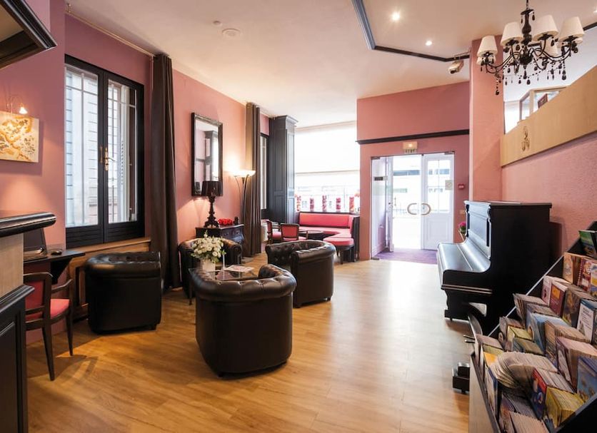 Hotel Roses Strasbourg lounge with leather chairs, piano, chandelier and street-facing seating area