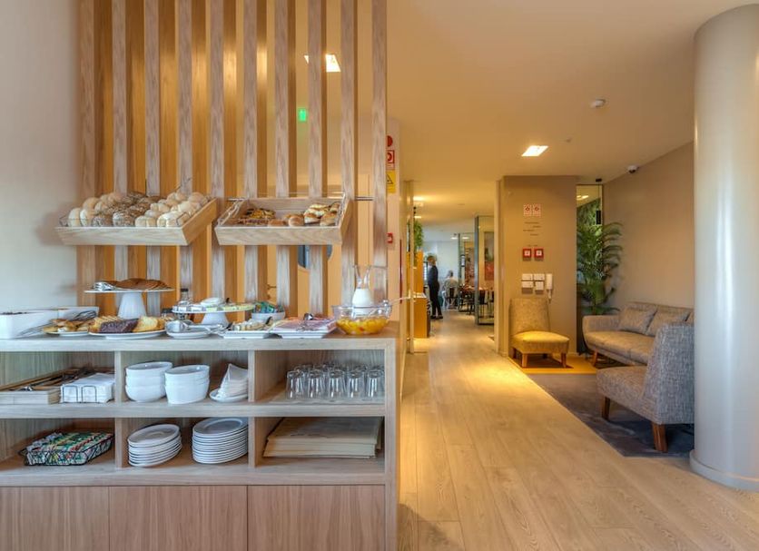 Hotel Spot Family Suites Porto breakfast buffet and lounge area with wood shelving and seating