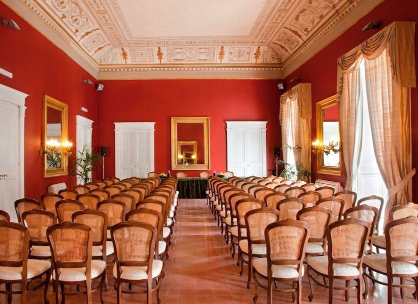 Napolit'amo Hotel Principe in Naples meeting room with rows of wooden chairs and red walls