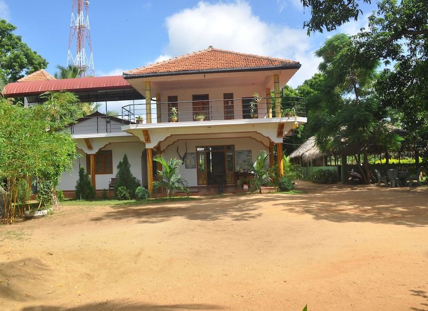 Thirumalai Park in Nilaveli: two-story hotel building with red roof, surrounded by trees and open grounds