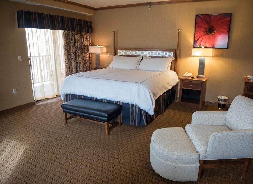 Mineral Palace Hotel & Gaming in Deadwood guest room with king bed, lounge chair, bench and balcony door