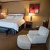 Mineral Palace Hotel & Gaming in Deadwood guest room with king bed, lounge chair, bench and balcony door