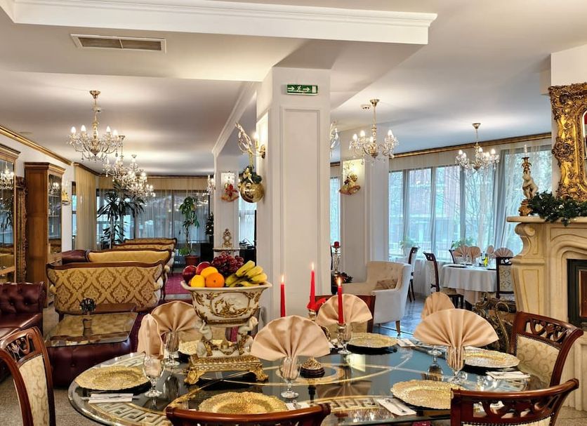 Elegant Lux Hotel in Bansko: ornate dining room with set table, chandeliers, and fireplace