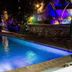 Elite Hotel Port Au Prince outdoor pool lit at night with lounge chairs and garden landscaping
