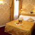 Cà Furlan Venice guest room with gold bedspread, fruit tray, patterned wallpaper and curtains