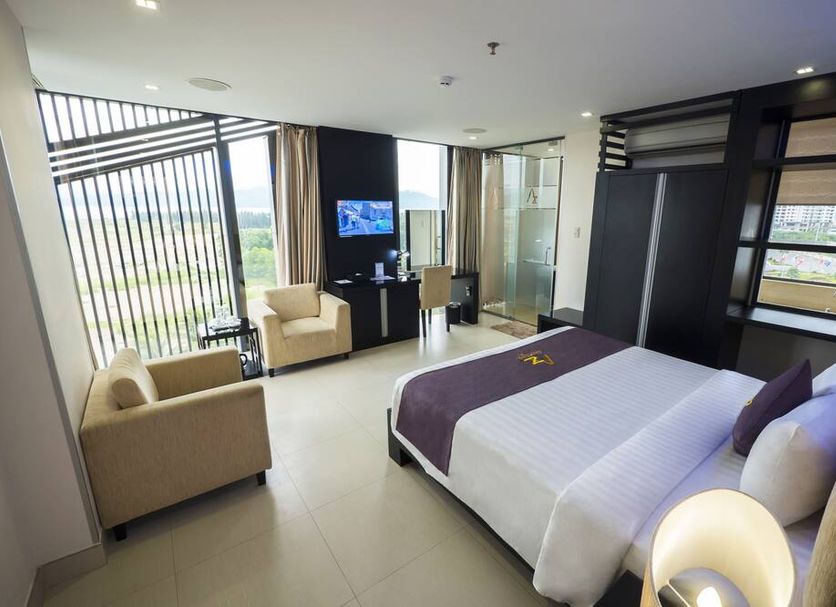 Azumaya Hotel Da Nang room with bed, seating area, and city view through large windows
