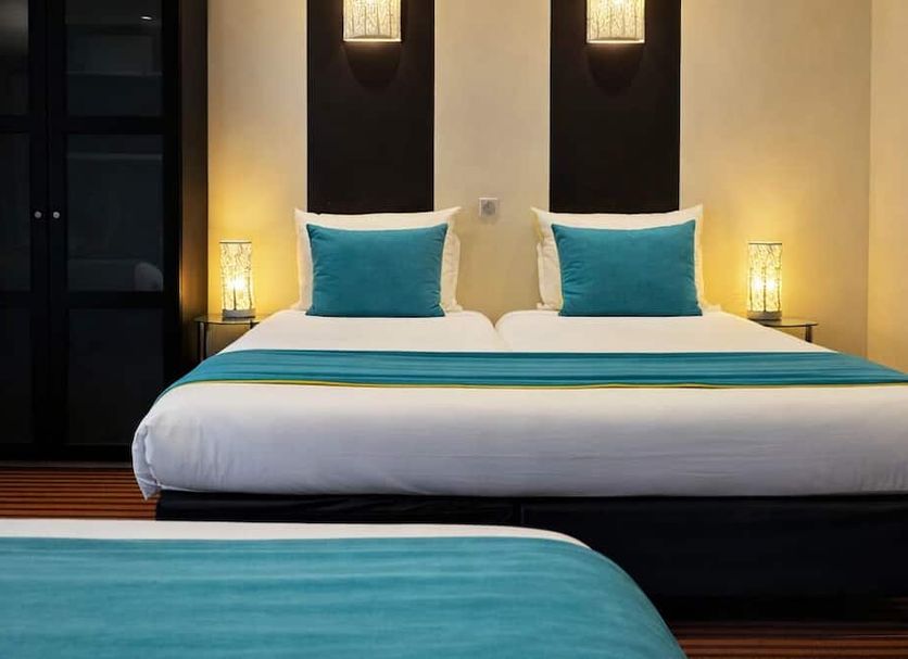 Hotel Pax Opera in Paris: twin bed setup with turquoise accents and warm bedside lamps