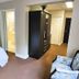 The Medicine Hat Villa guest room with bed, armchair, wardrobe, and bathroom doorway in Medicine Hat